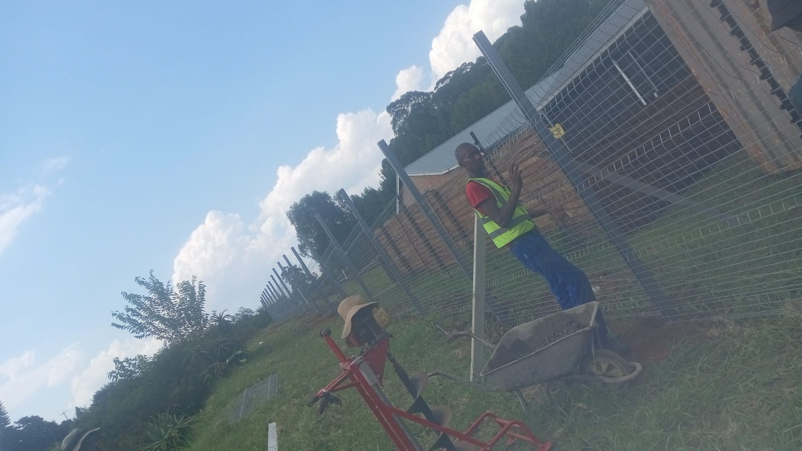 Worker installing wire mesh fencing alongside a brick building